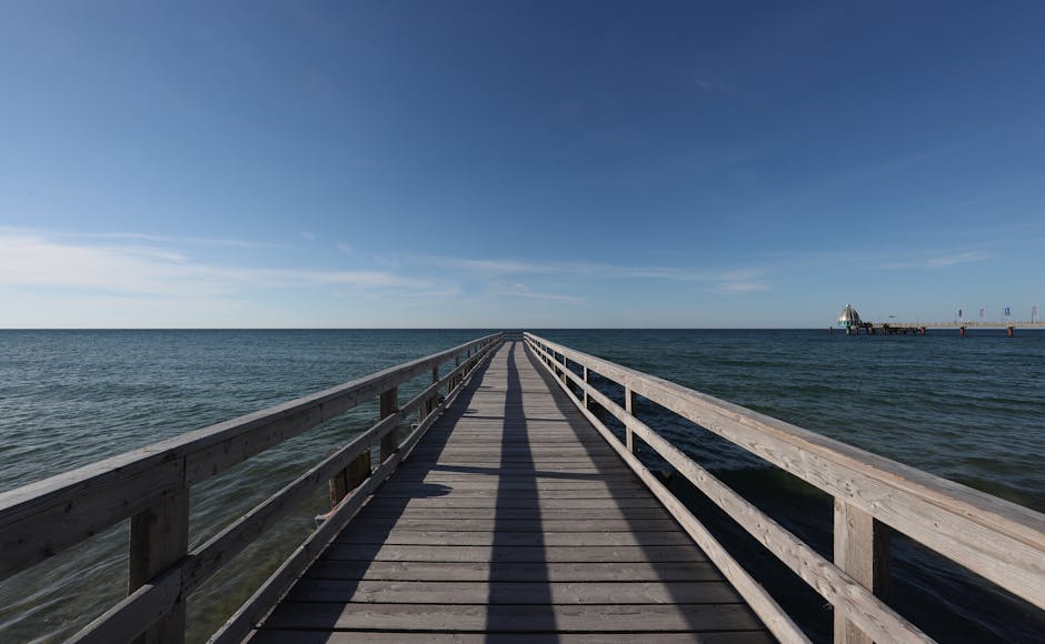 A serene view from a wooden pier stretching into the vast Baltic Sea under a clear blue sky.